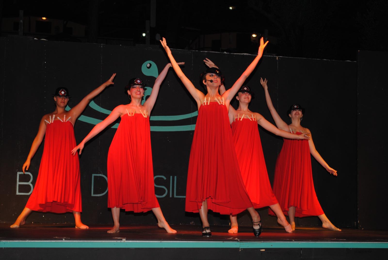 Cinque ballerine in abito rosso con braccia aperte
